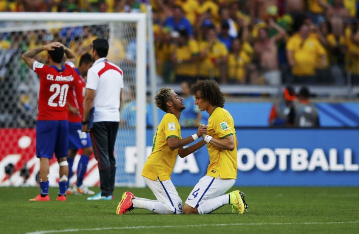 Игроки сборной Бразилии Давид Луис (справа) и Неймар радуются победе в матче против Чили. ©REUTERS