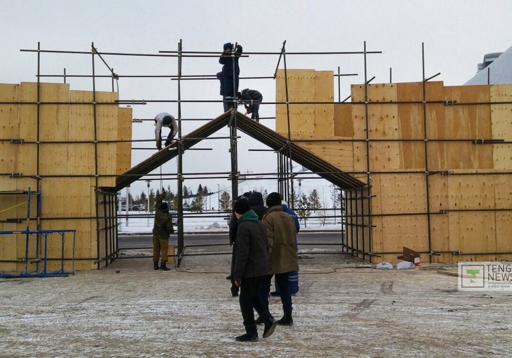 На площади недалеко от ТРЦ "Хан Шатыр", вот за этой аркой, днем и ночью ведутся работы по возведению главного ледового городка.  