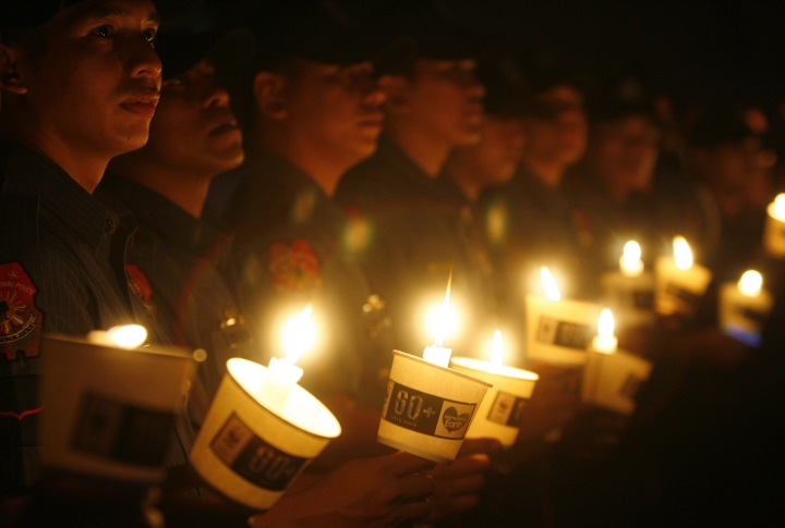 Филиппинские полицейские держат в руках свечи в поддержку акции. Фото REUTERS/Cheryl Ravelo©