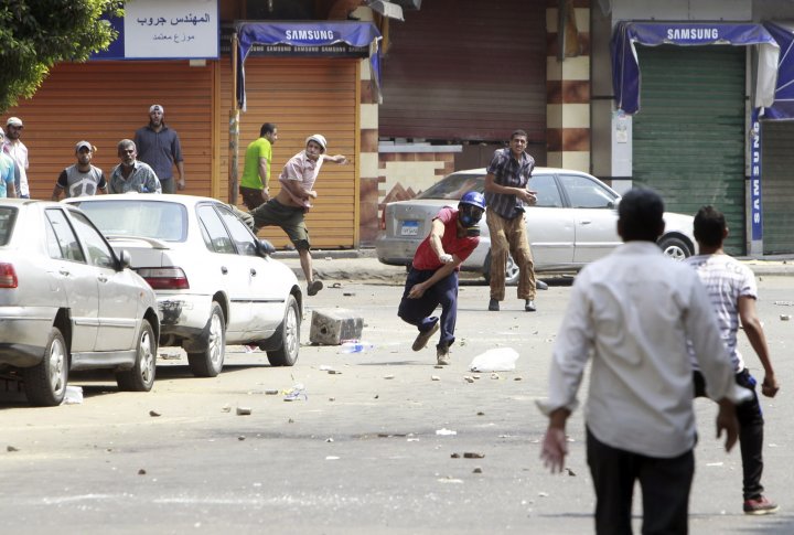 Сторонники свергнутого президента Египта Мохаммеда Мурси бросают камни в местных жителей во время столкновений в центре Каира 13 августа 2013 года. Фото ©REUTERS