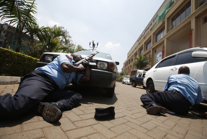 Полиция укрывается за автомобилем у торгового центра в Найроби 21 сентября 2013 г. Фото ©REUTERS
