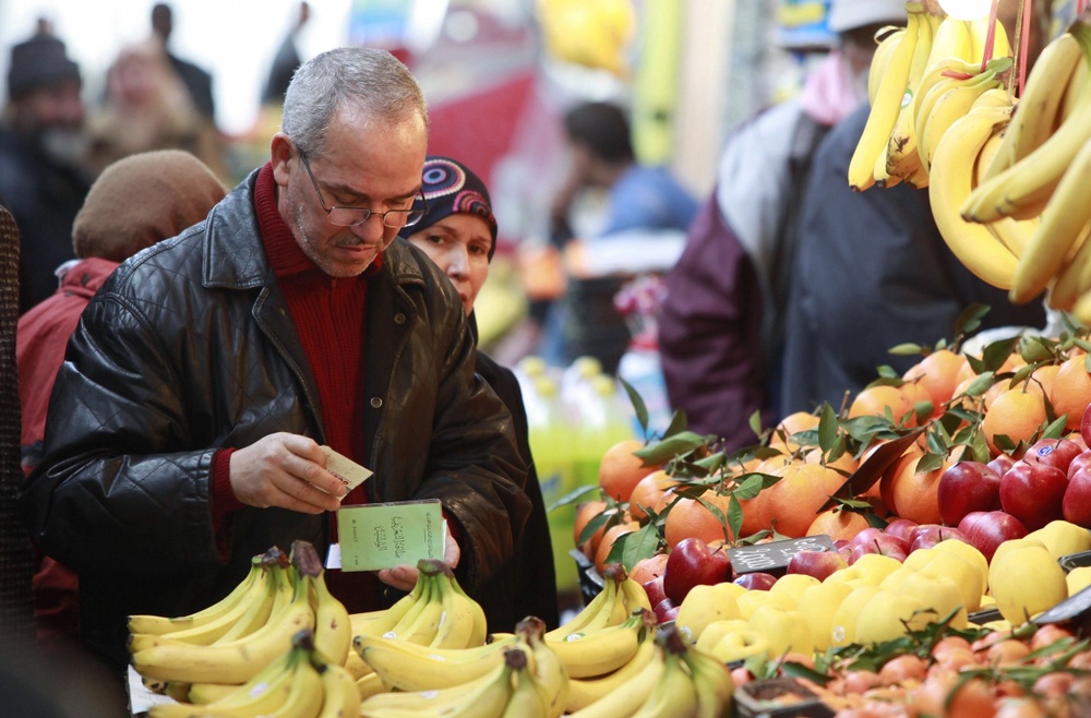 Мужчина покупает банан у прилавка с фруктами. ©REUTERS/Louafi Larbi