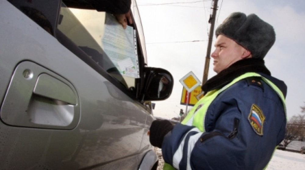 Работник дорожно-патрульной службы ГИБДД проверяет документы у владельца праворульного автомобиля. ©РИА Новости
