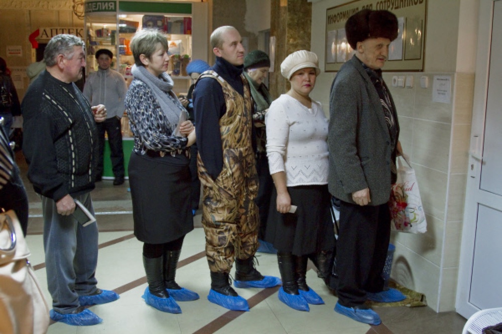 Люди стоят в очереди у кабинета в бахилах. Фото РИА Новости/Алексей Мальгавко©