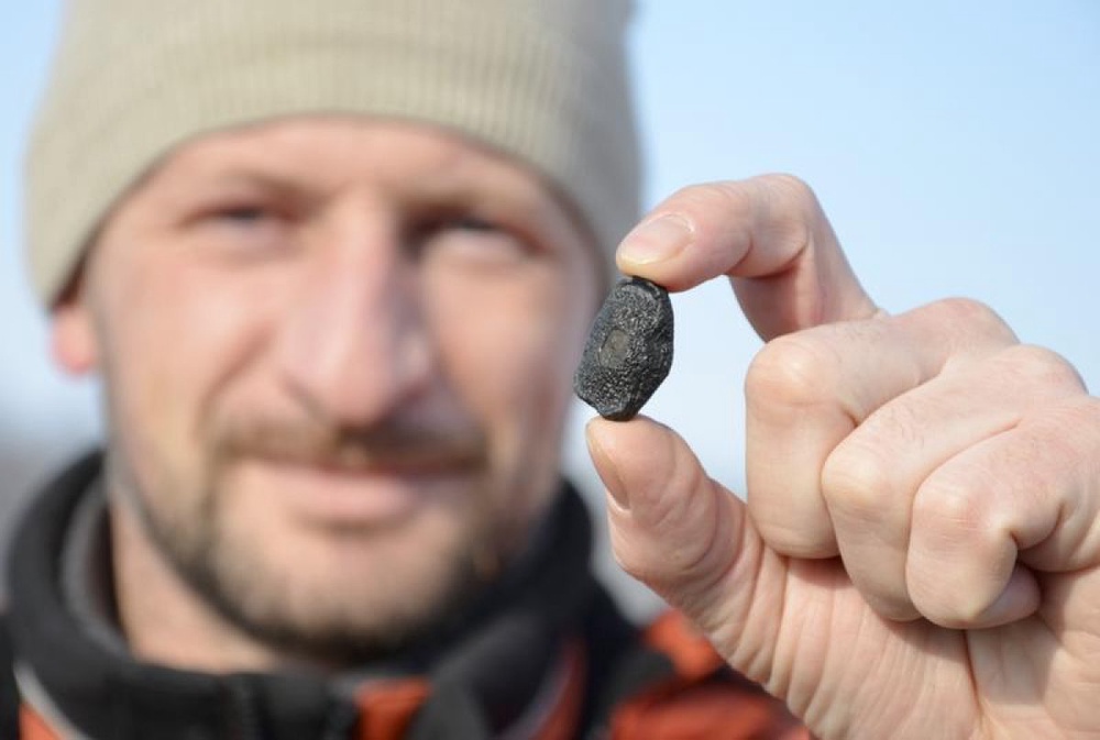 Местный житель с фрагментом метеорита, найденным в окрестностях Челябинска. Фото ©REUTERS