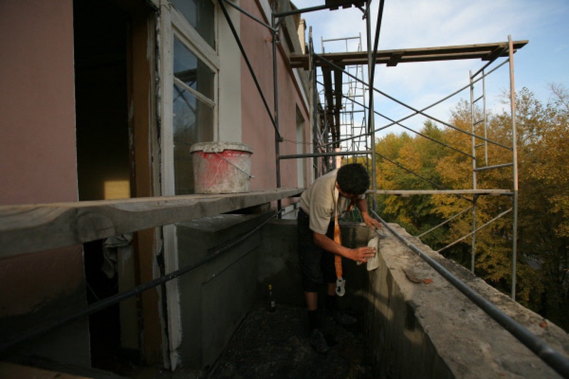 Рабочий ремонтирует балкон многоэтажного дома. Фото ©РИА Новости
