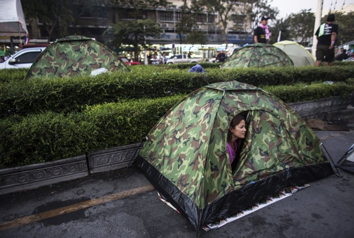 Женщина выглядывает из палатки в лагере протестующих возле монумента Демократии в Бангкоке. ©REUTERS