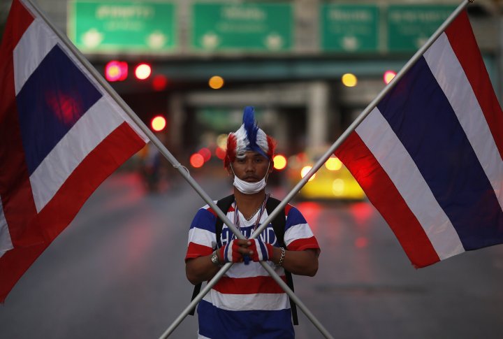 Протестующий держит национальные флаги Таиланда в центре Бангкока. ©REUTERS
