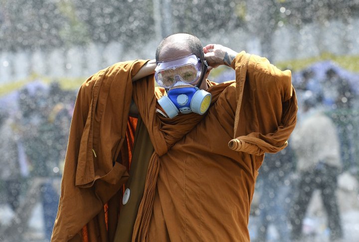 Тайский буддийский монах надевает противогаз, так как полиция использует водометы и слезоточивый газ против демонстрантов на баррикадах у Дома правительства в Бангкоке. ©REUTERS