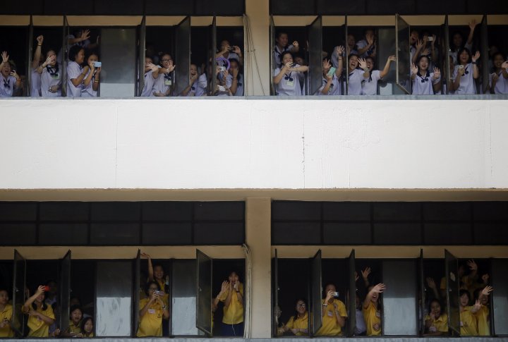 Студенты приветствуют демонстрантов, проходящих мимо их школы в Бангкоке. ©REUTERS