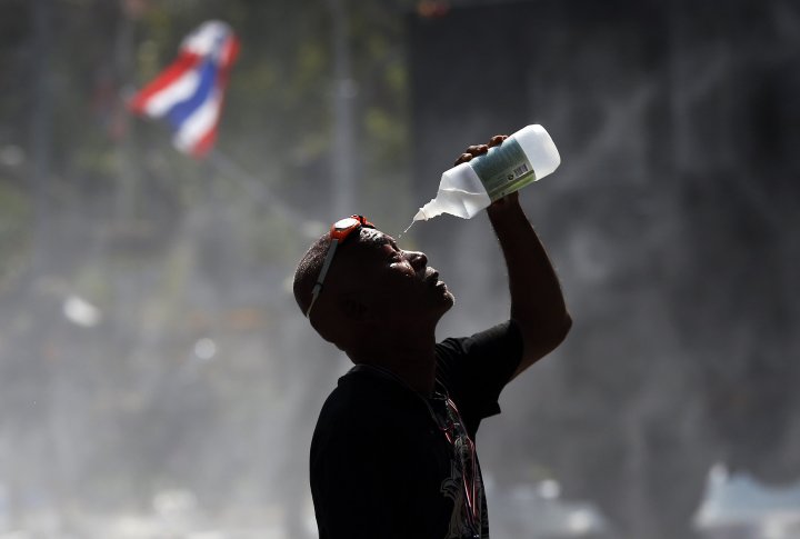 Демонстрант льет воду на лицо, пытаясь избежать поражения слезоточивым газом. ©REUTERS