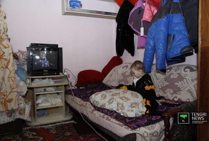 Маленькая Айсулу смотрит телевизор. Помимо пары игрушек, это единственное развлечение для детей. Фото Дмитрий Хегай©
