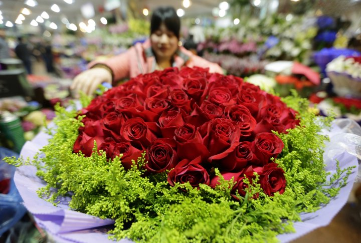 Китай. Флорист украшает букет из 99 роз на рынке в Пекине. ©REUTERS