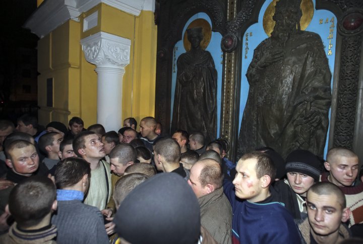 Члены МВД в штатском, которые были задержаны антиправительственными демонстрантами в ходе столкновений, стоят перед православной церковью после того, как они получили свободу, в центре Киева 21 февраля 2014 года. ©REUTERS
