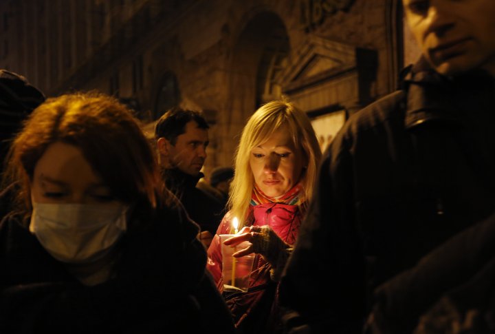 Женщина, которая держит свечу, принимала участие в передаче более десятка трупов из лобби отеля в местную больницу после столкновений с полицией на майдане Независимости в Киеве 20 февраля 2014 года. ©REUTERS