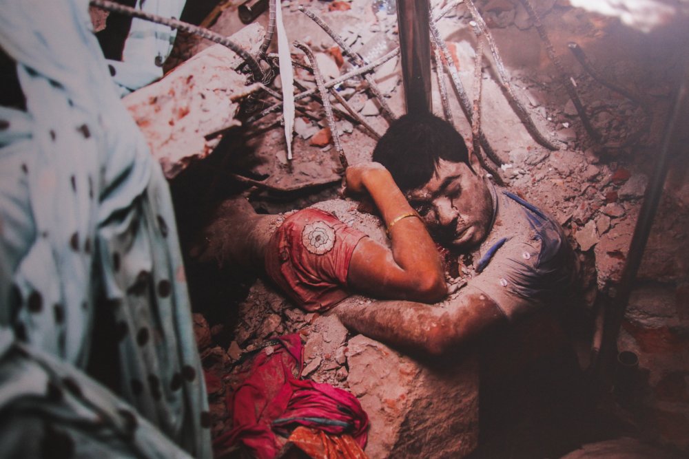 Фотография Таслимы Ахтер из Бангладеша на тему обрушения комплекса "Рана Плаза". Работа затрагивает вопросы безопасности труда. Известно, что изначально здание было рассчитано на 5 этажей, но так как были надстроены еще 6 и 7 этажи, оно рухнуло. При обрушении погибли 1127 человек.