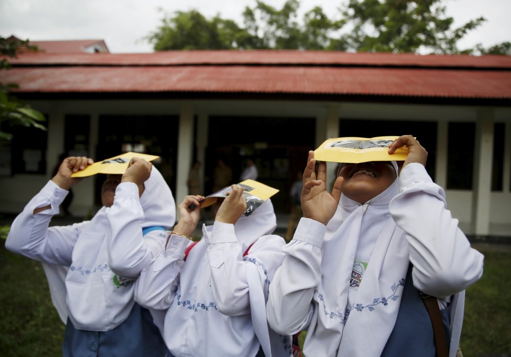 Студенты проверяют свои самодельные фильтры перед началом солнечного затмения. Индонезия. © REUTERS