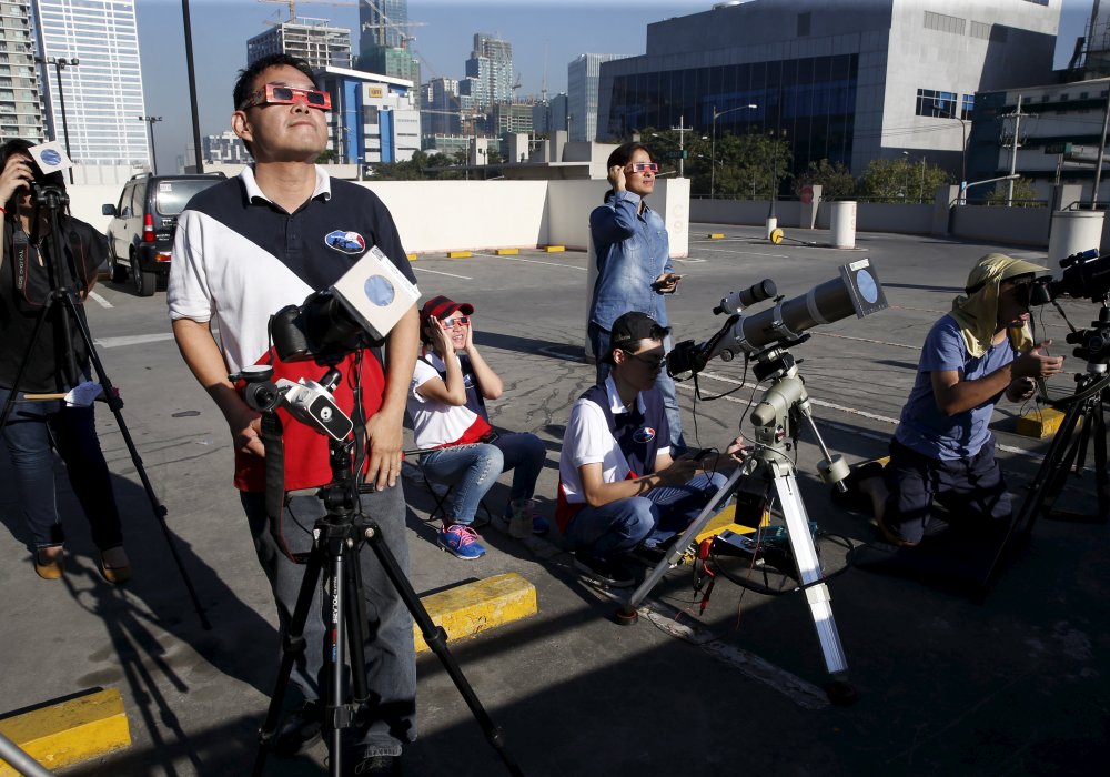 Члены Астрономической Лиги Филиппин занимают позиции на крыше для наблюдения частичного солнечного затмения. © REUTERS