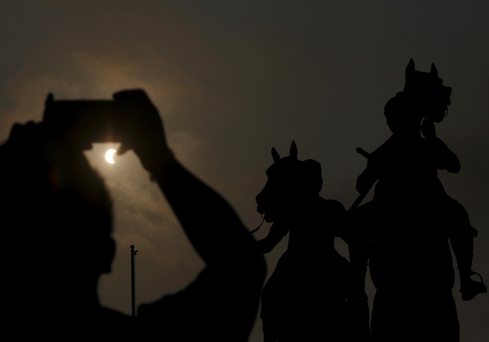 Человек с помощью смартфона документирует частичное солнечное затмение в Пномпене (Камбоджа). © REUTERS