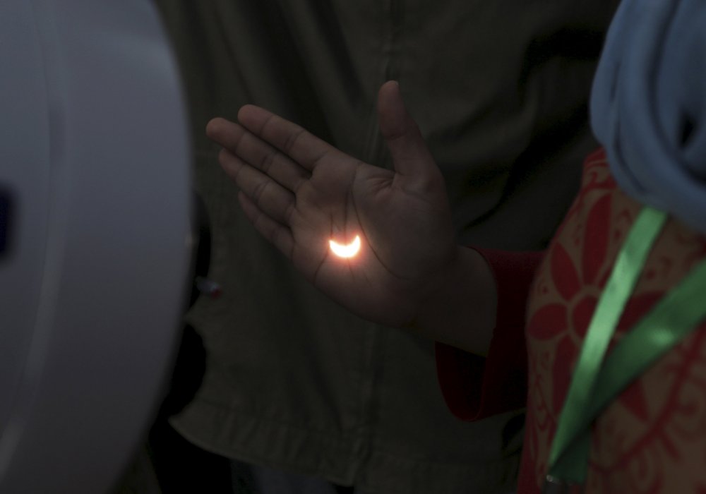 Солнечное затмение отражается на руке человека. Палембанг, провинция Южная Суматра, Индонезия. © REUTERS