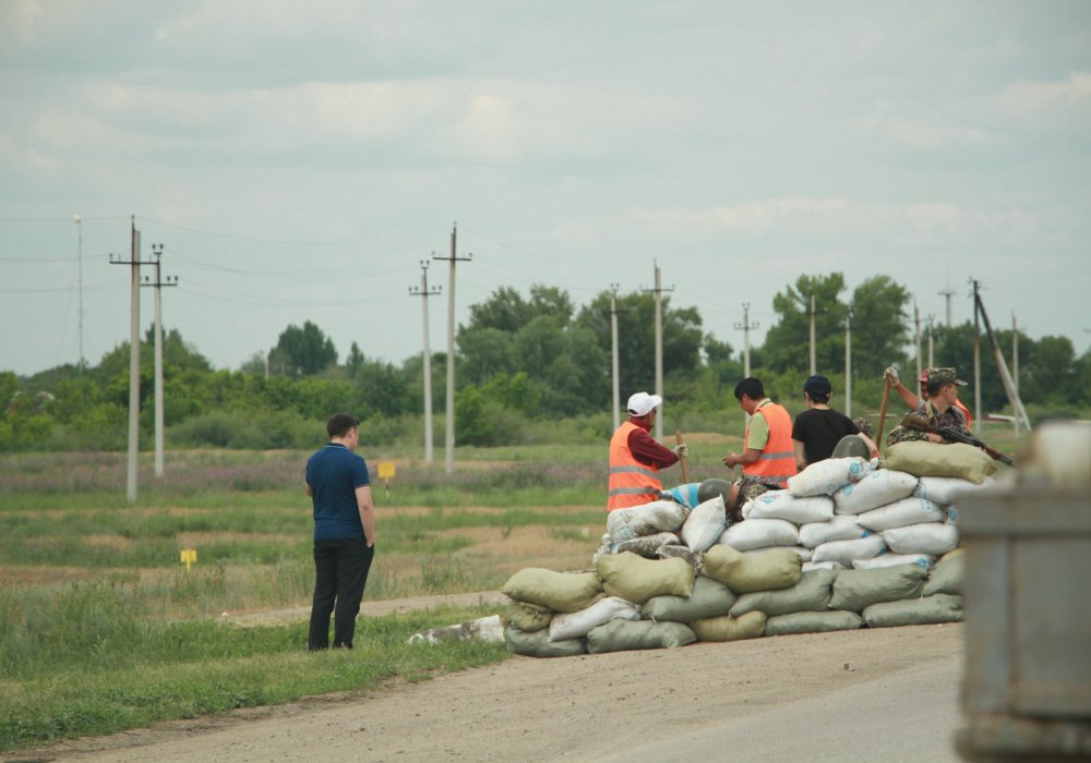 Рабочие возводят укрепление для полицейских из мешков с песком на выезде из Актобе