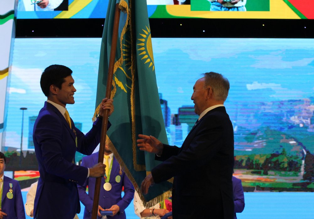 Елеусинов возвращает врученный перед Олимпиадой Государственный флаг страны Президенту.