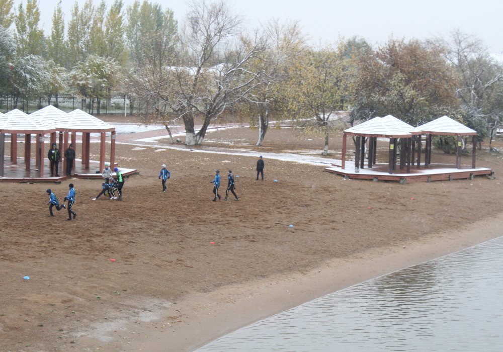 Дети играют в футбол на городском пляже.