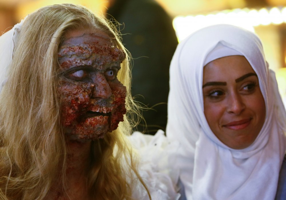 Женщина-мусульманка фотографируется с участником парада зомби в честь Хэллоуина. Эссен, Германия. REUTERS ©