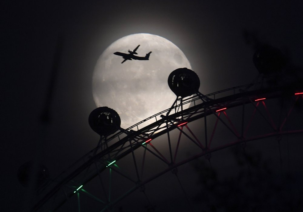 London Eye и пролетающий самолет на фоне "Суперлуны". Фото REUTERS/Toby Melville©