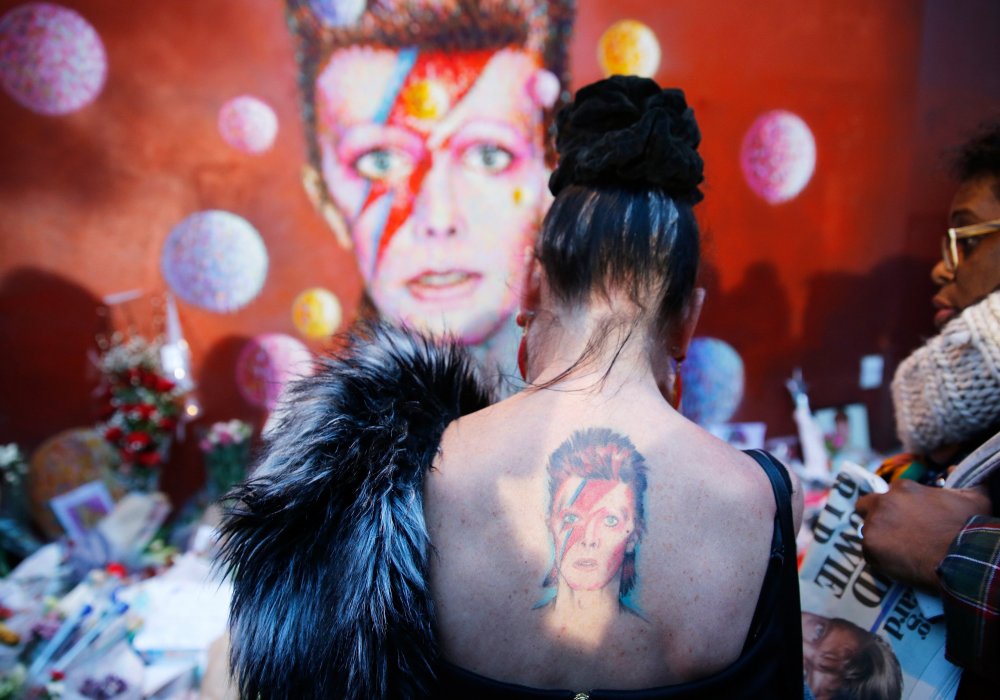 <p>Поклонница Дэвида Боуи с татуировкой Боуи в образе Зигги Стардаста принесла цветы к дому, где жил певец. Музыкант скончался в возрасте 69 лет. Фото REUTERS/Stefan Wermuth©</p>