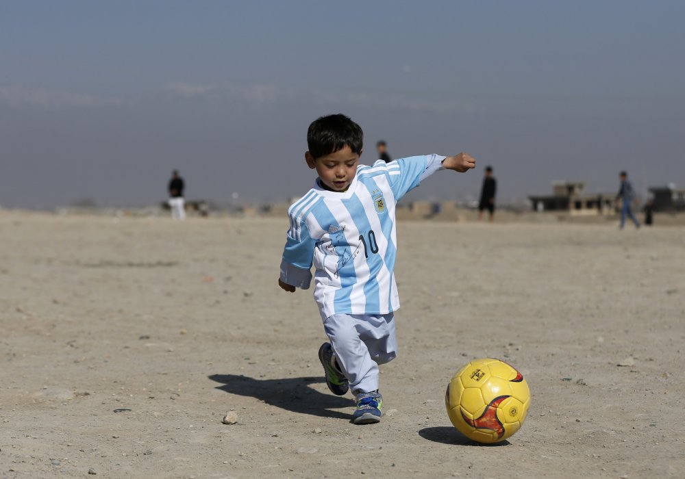<p>Пятилетний афганский мальчик по имени Муртаза Ахмади играет в футбол в майке, подписанной Лионелем Месси. В конце 2015 года мировые медиа облетела фотография его же в майке сборной Аргентины, сделанной из полиэтиленового пакета. Менеджеры Месси нашли мальчика в Кабуле и познакомили его с кумиром. Фото REUTERS/Omar Sobhani©</p>