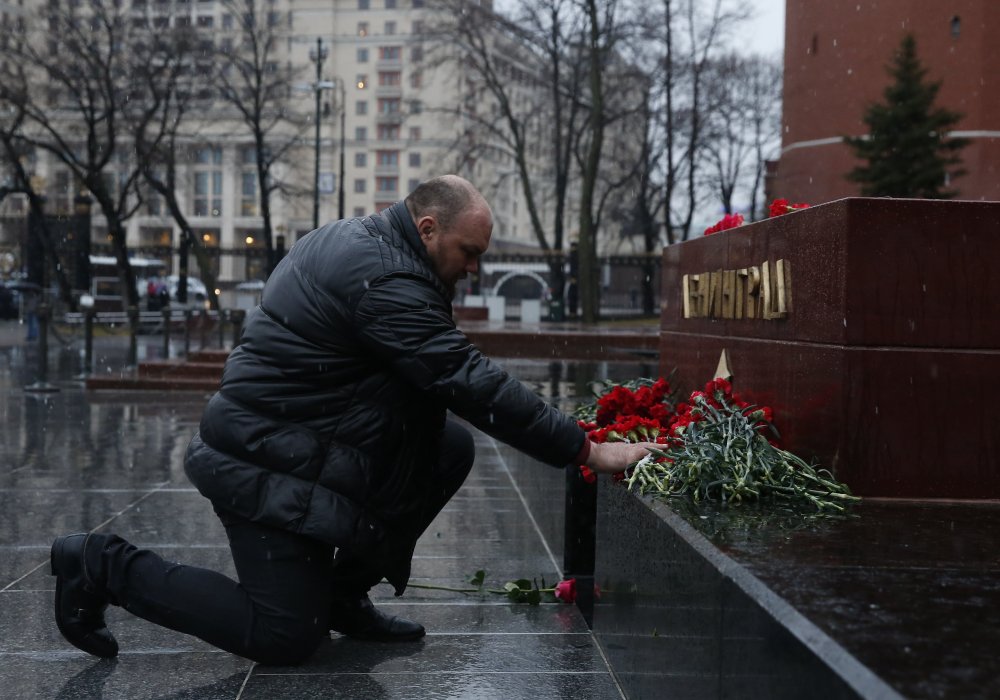 Мужчина возлагает цветы к мемориалу "Ленинград" у Кремлевской стены в Москве. Фото REUTERS/Maxim Shemetov