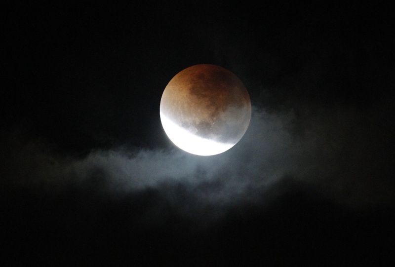 Лунное затмение в первые часы в просвете туч над Сиднеем, Австралия. ©REUTERS/Tim Wimborne