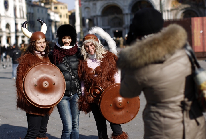 Туристы фотографируются с костюмированными участниками карнавала в Венеции. Фото ©REUTERS