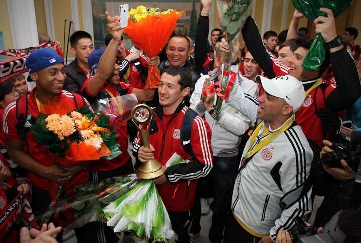 Капитан команды в окружении остальных участников команды несет Кубок, чтобы показать его болельщикам алматинского клуба 