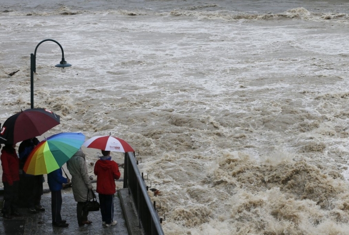 Люди стоят рядом с мостом у реки Штайр во время проливных дождей в одноименном австрийском городе Штайр. Фото ©REUTERS