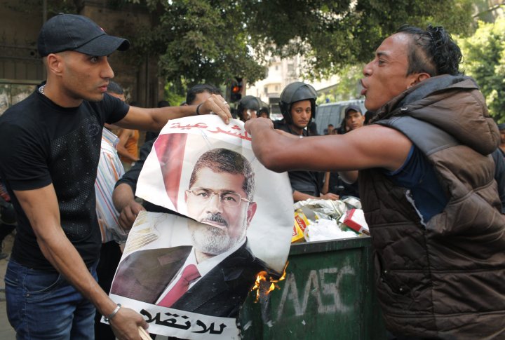 Местные жители сжигают плакат свергнутого президента Мохаммеда Мурси, который бросили его сторонники во время столкновений в центре Каира 13 августа 2013 года. Фото ©REUTERS