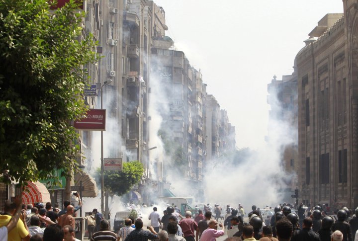 Сторонники свергнутого президента Египта Мохаммеда Мурси убегают от слезоточивого газа. На переднем плане местные жители. Во время столкновений в центре Каира 13 августа 2013 года. Фото ©REUTERS