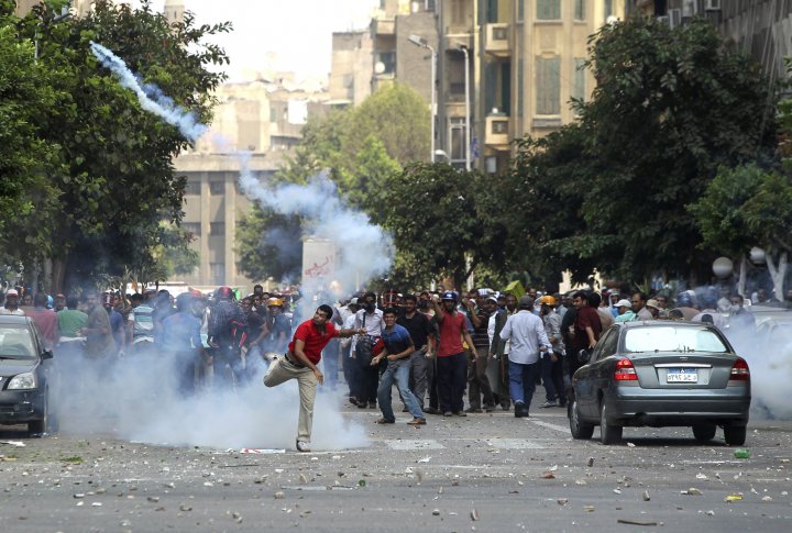 Сторонник свергнутого президента Мохаммеда Мурси бросает гранату со слезоточивым газом обратно в сторону полиции в ходе столкновений в центре Каира 13 августа 2013 года. Фото ©REUTERS