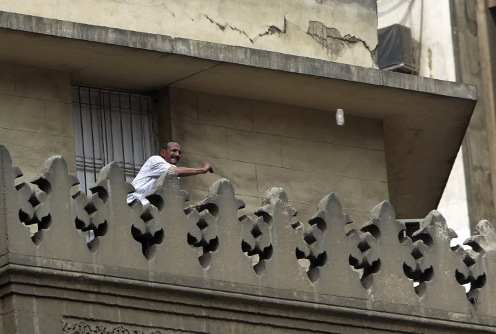 Сторонник нового правительства швыряет бутылку в протестующих во время столкновений в центре Каира 13 августа 2013 года. Фото ©REUTERS