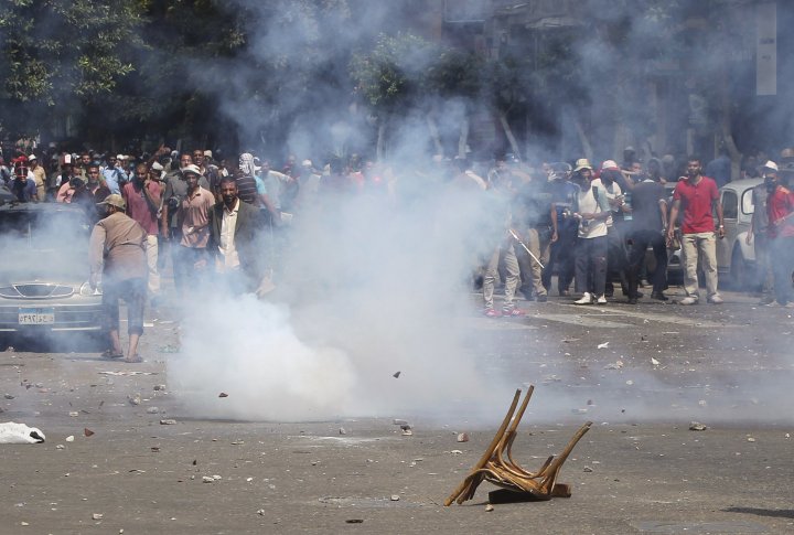 Сторонники свергнутого президента Египта Мохаммеда Мурси убегают от слезоточивого газа. Во время столкновений в центре Каира 13 августа 2013 года. Фото ©REUTERS