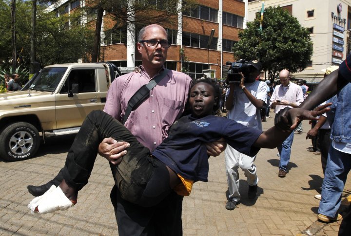 Журналист спасает раненую женщину у торгового центра в Найроби 21 сентября 2013 г. Фото ©REUTERS