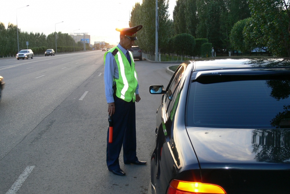Сотрудник дорожной полиции проверяет документы у водителя транспортного средства. Фото Назымгуль Кумыспаева©