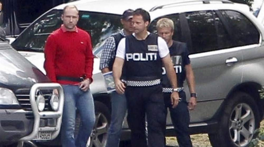 Андерс Брейвик (в красном)с полицейским эскортом. ©REUTERS