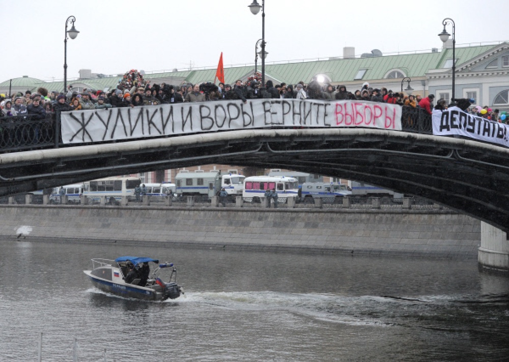 Участники митинга "За честные выборы" на Лужковом мосту у Болотной площади стоят с транспарантом с надписью: "Жулики и воры, верните выборы". Фото РИА Новости