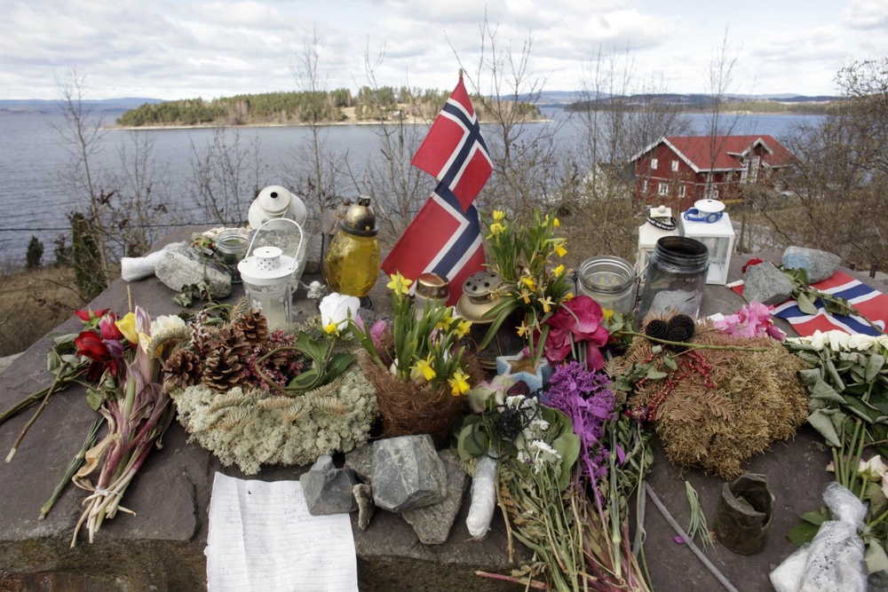 Норвежские флаги, свечи и цветы на берегу у острова Утойя. Фото ©REUTERS