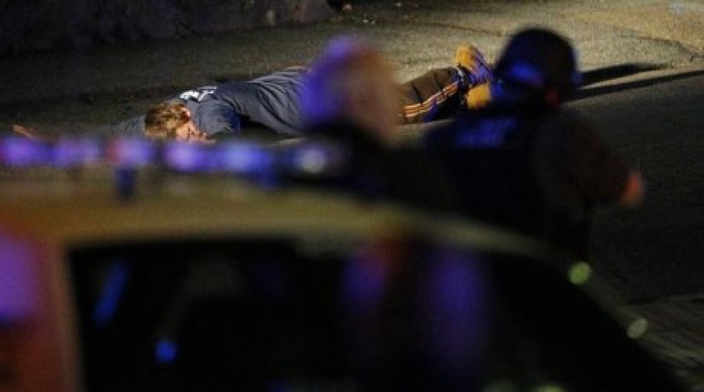 Полицейские держат человека на земле на месте убийства полицейского во время розыска подозреваемых. Фото ©REUTERS