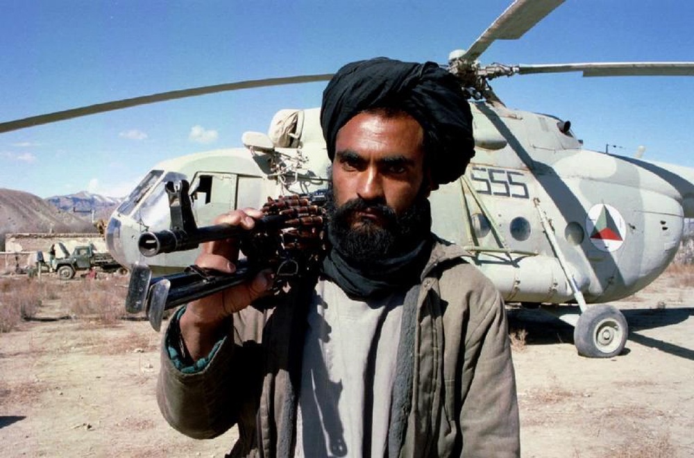 Боевик талибов на фоне вертолета Ми-8. Фото ©REUTERS