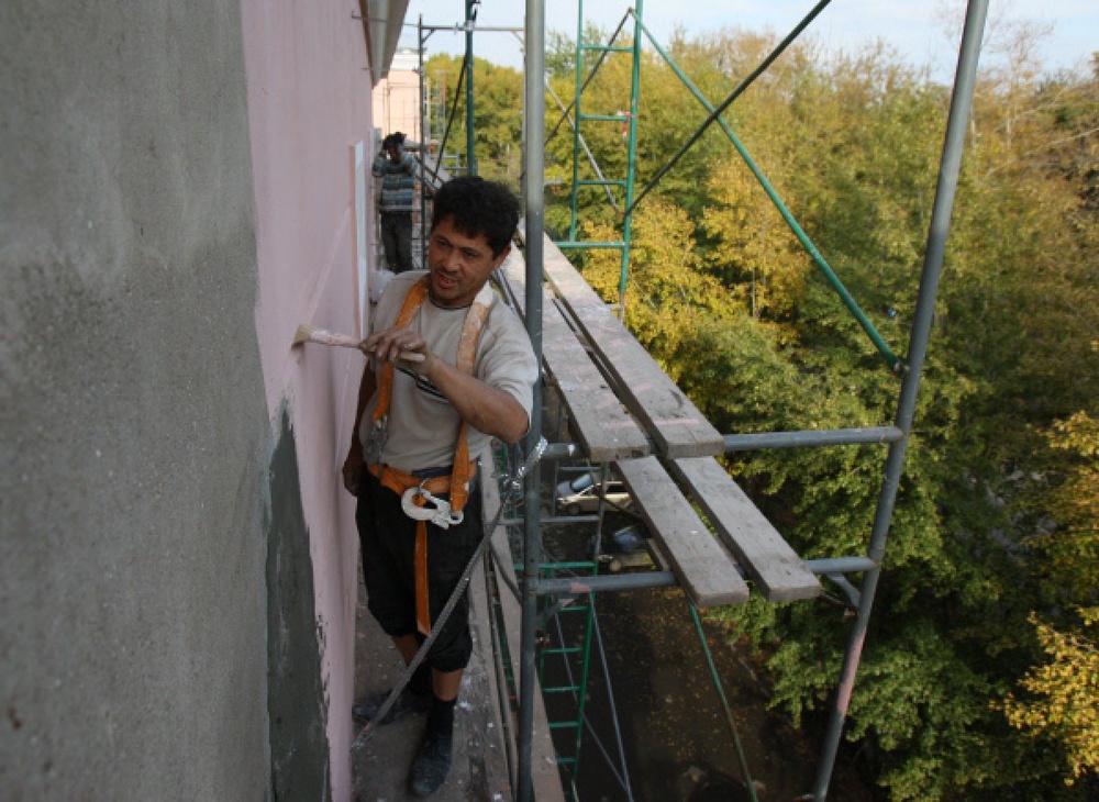Рабочие ремонтируют фасад многоэтажного дома. Фото ©РИА Новости