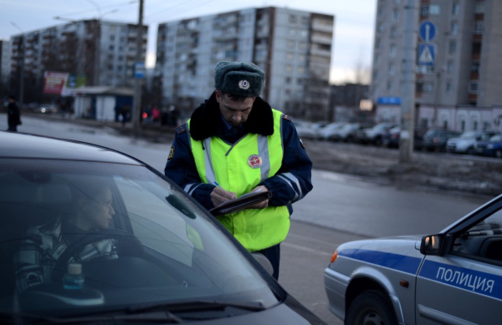 Сотрудник дорожно-патрульной службы ГИБДД проверяет документы у водителя. ©РИА Новости
